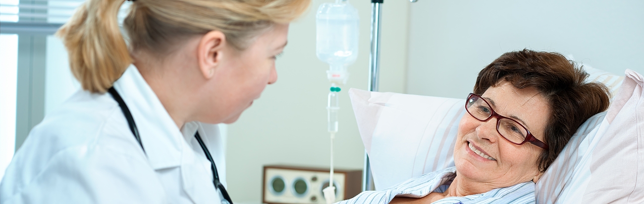 Ärztin bei Visite Ärztin mit Patientin am Krankenbett