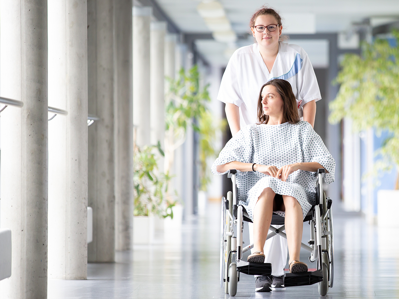 Schwester schiebt Patientin durch den Flur
