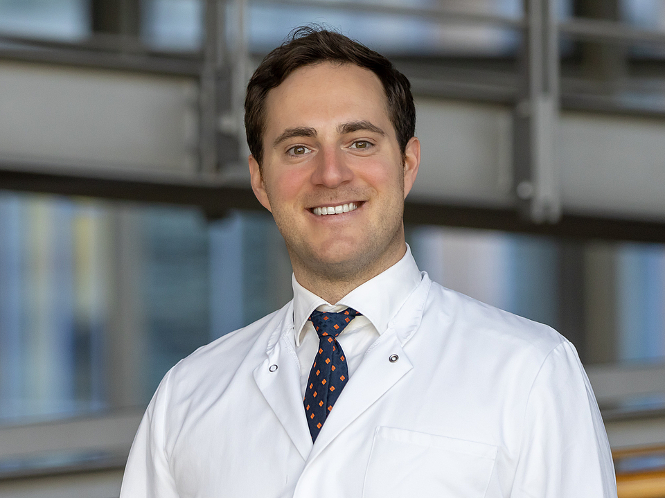 Arzt lächelt in die Kamera.