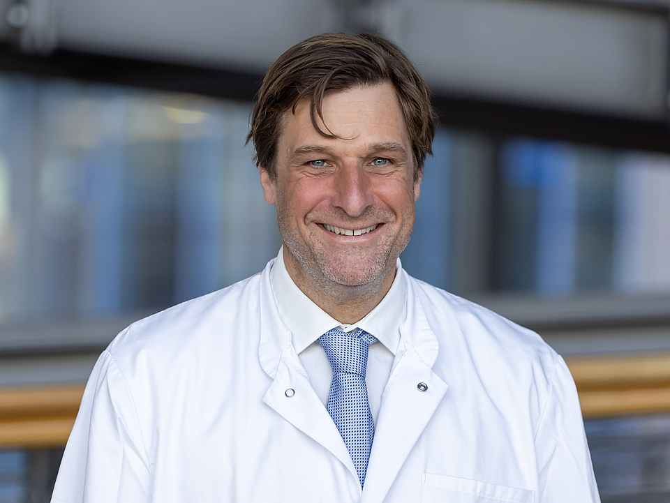 Arzt lächelt in die Kamera.