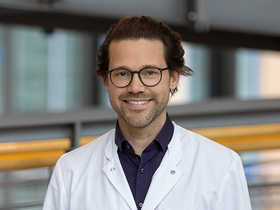 Arzt lächelt in die Kamera.