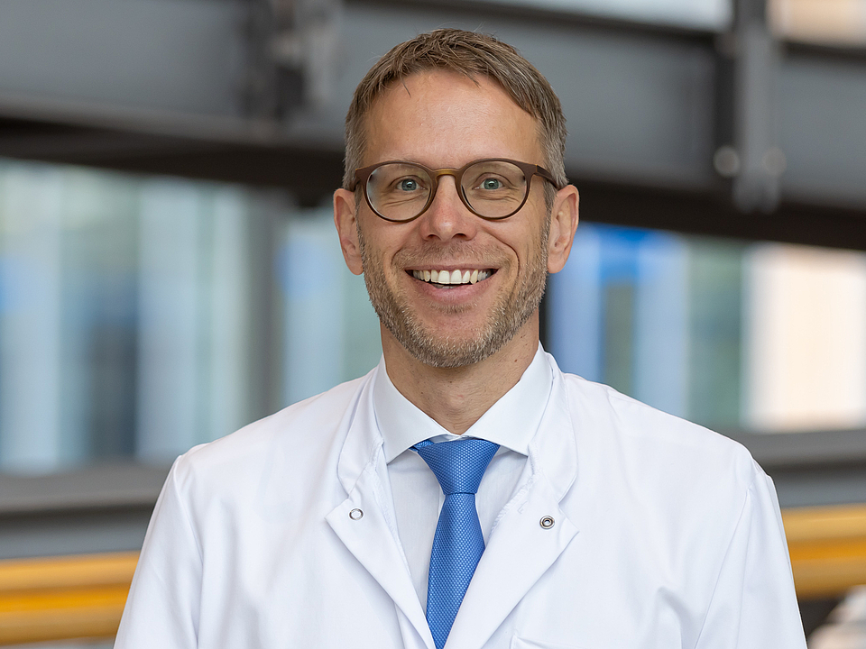 Arzt lächelt in die Kamera.