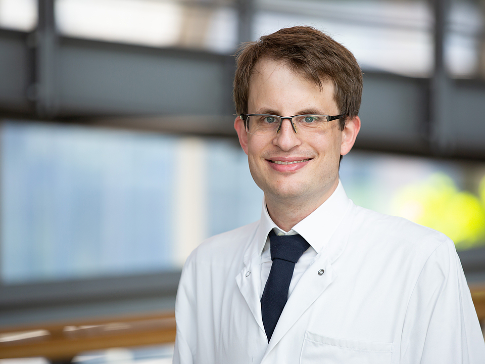 Ein Arzt lächelt in die Kamera.