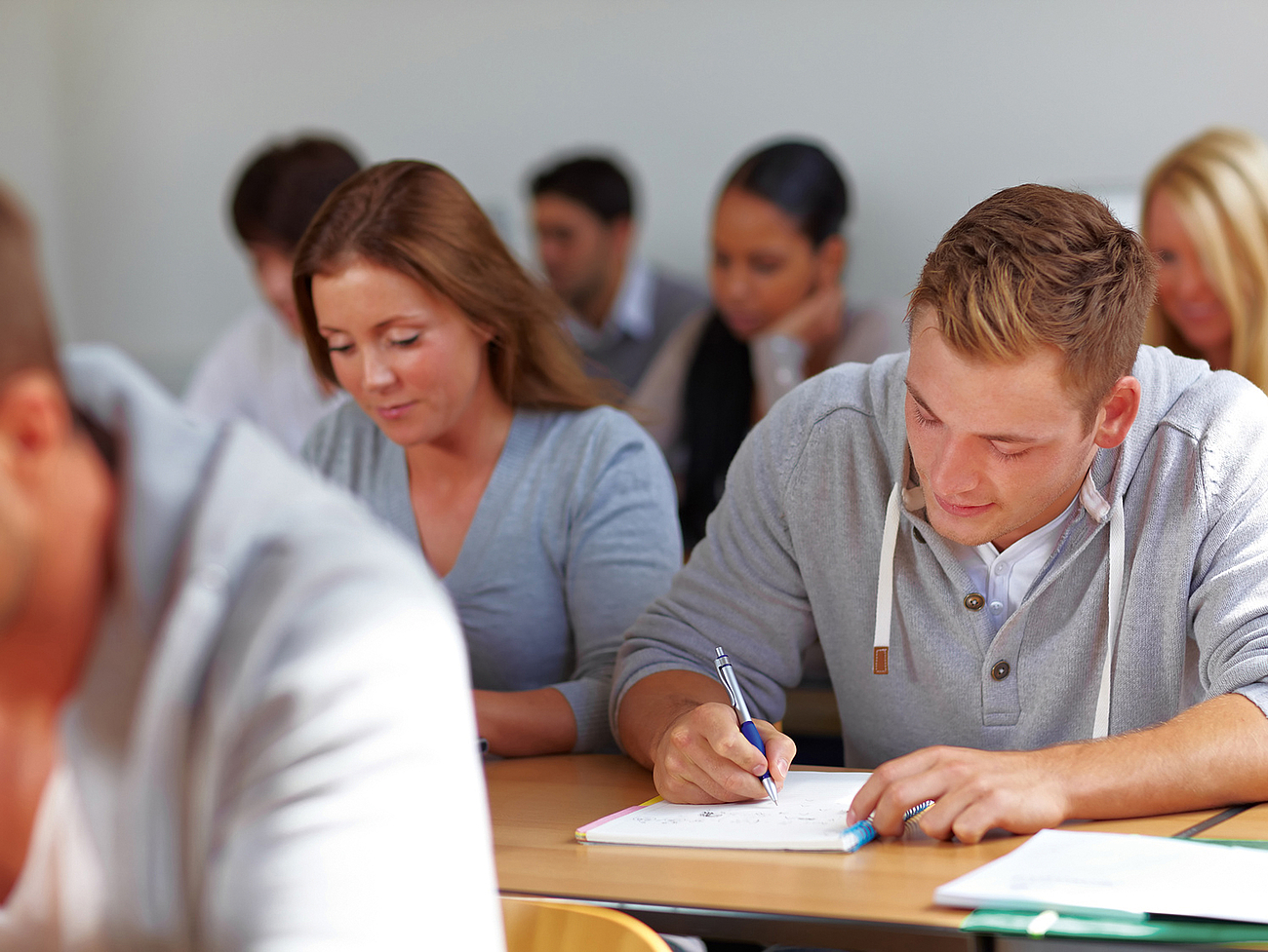 Berufsschüler sitzen in einem Klassenzimmer und schreiben Notizen.