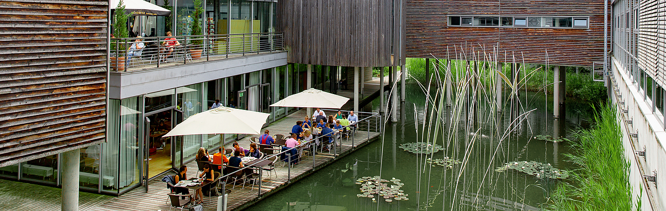Sitzplätze der Kantine im Garten neben einem Teich