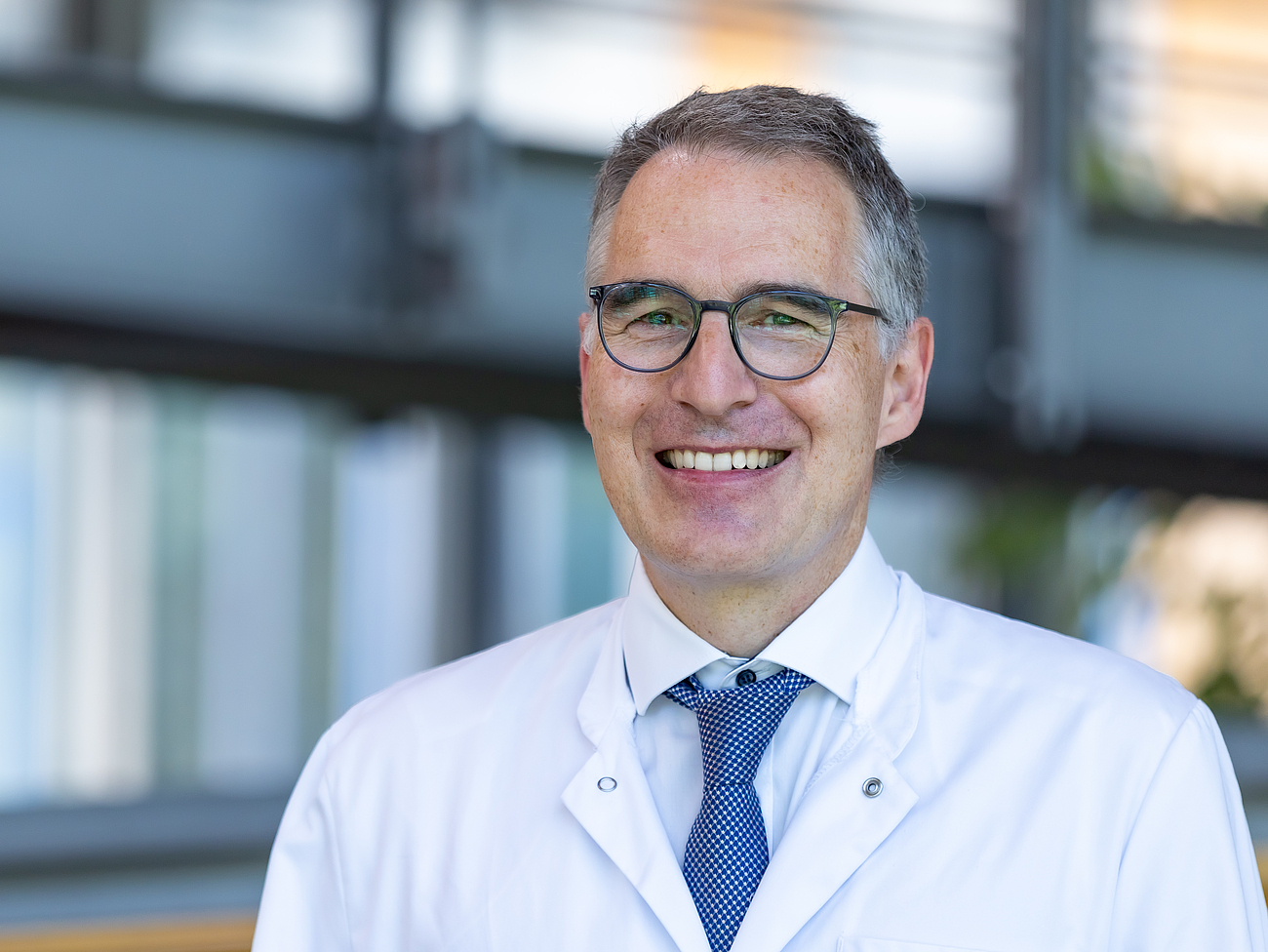 Arzt lächelt in die Kamera.