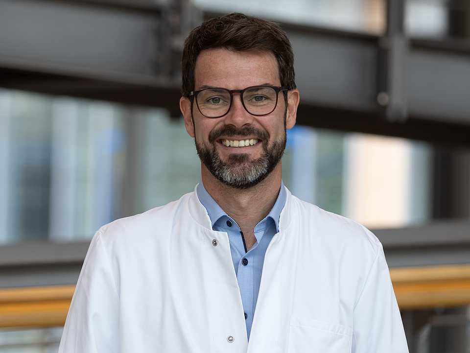 Arzt lächelt in die Kamera.