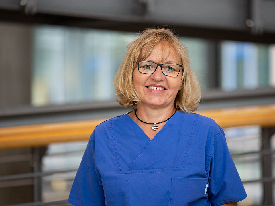 Pflegerin lächelt in die Kamera.