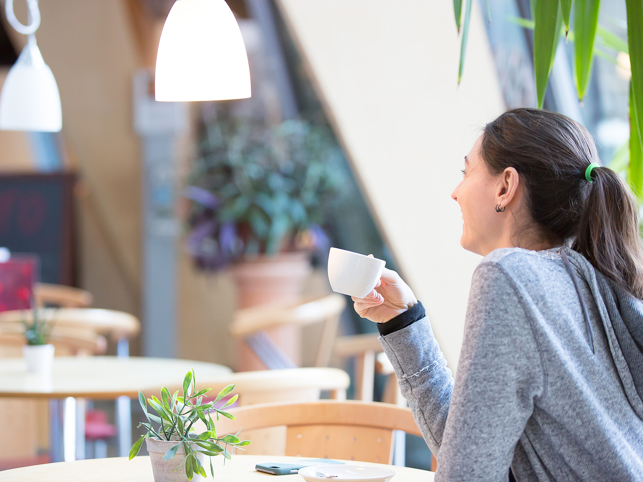 Eine Patientin sitzt im Bistro und trinkt einen Kaffee.