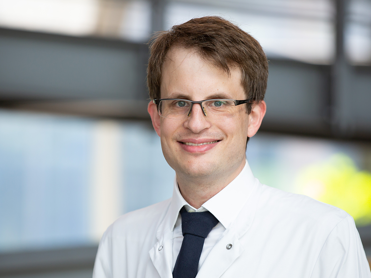 Ein Arzt lächelt in die Kamera.