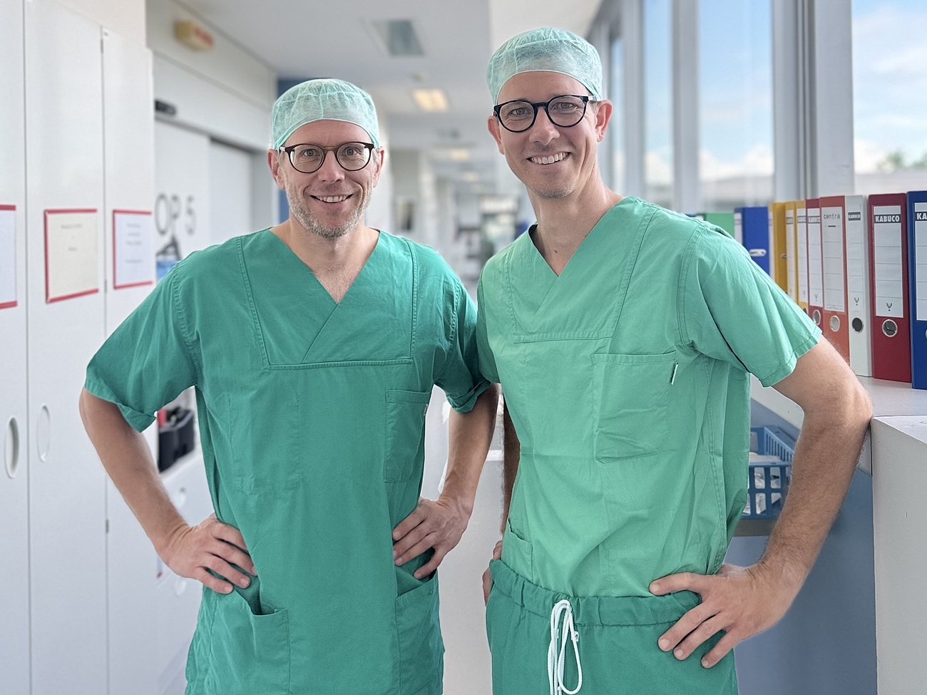 Zwei Ärzten stehen im Flur in OP-Kleidung.