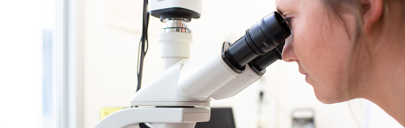 Fachkraft mit Mikroskop