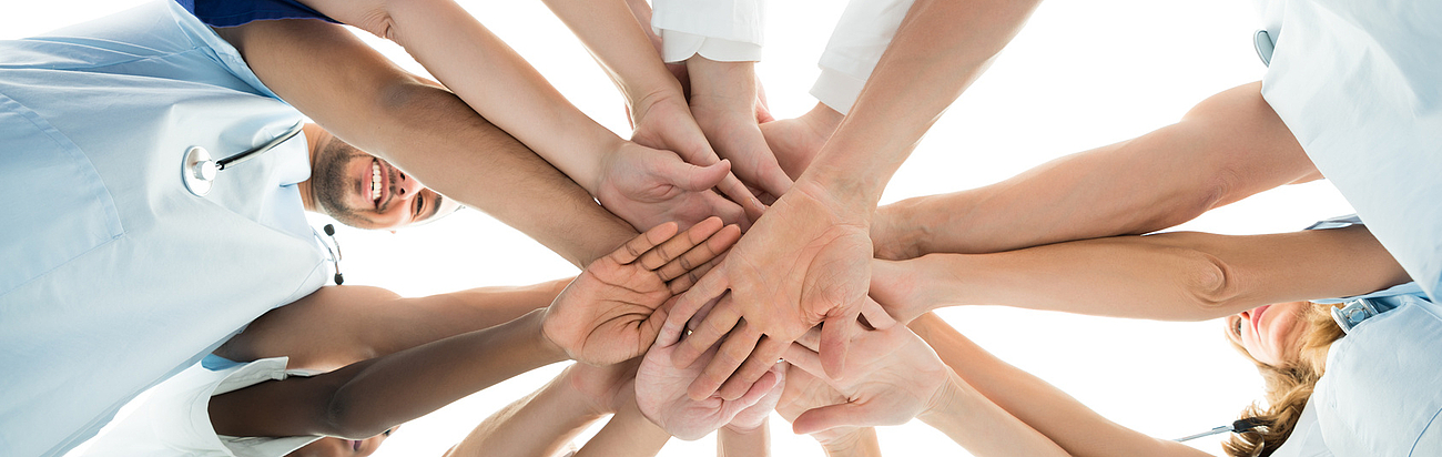 Mitarbeiter bilden Kreis und legen ihre Hände aufeinander