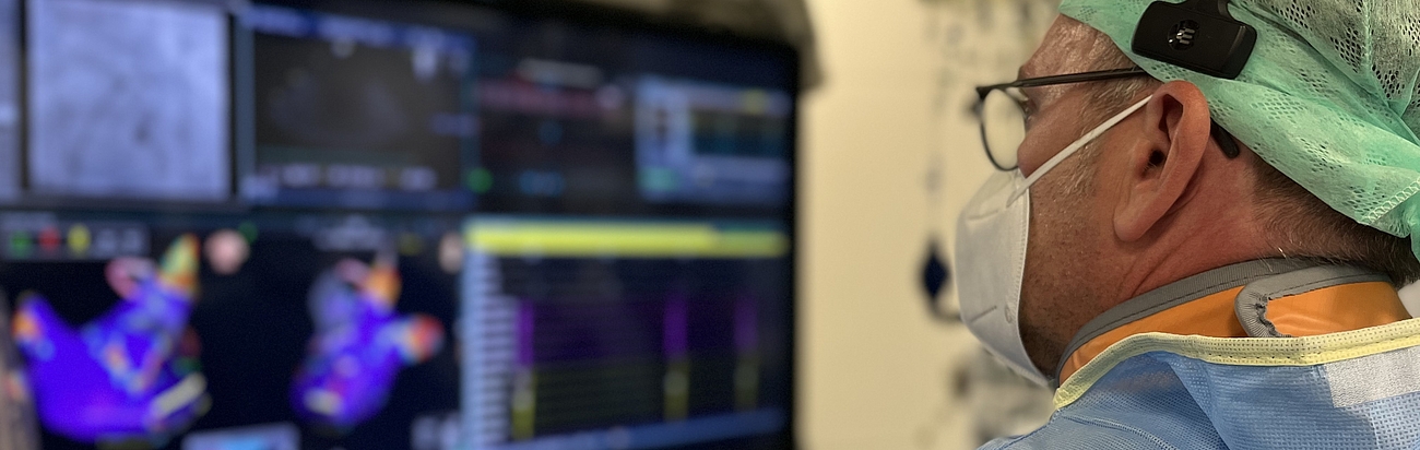 Ein Arzt sieht in einer OP auf einen Bildschirm.