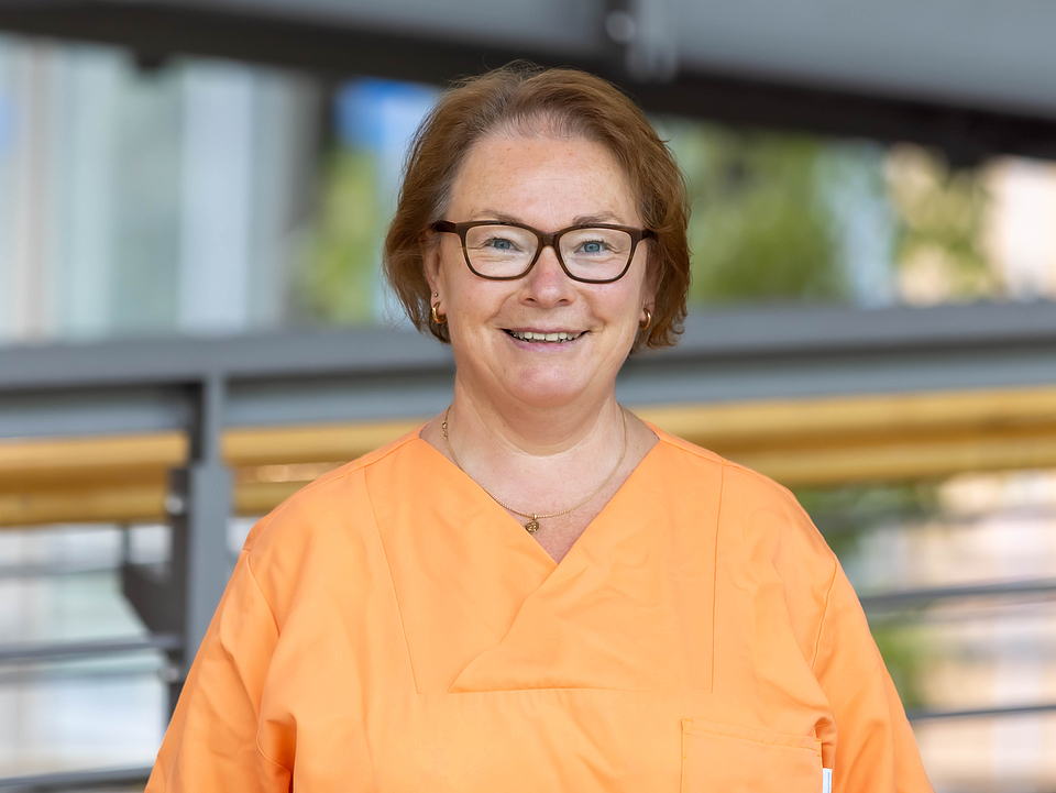 Pflegerin lächelt in die Kamera.