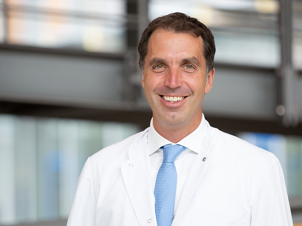 Ein Arzt lächelt in die Kamera.