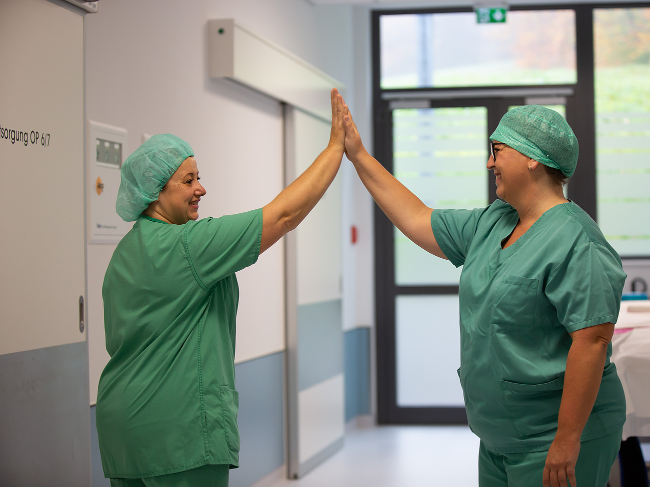 Zwei Pflegerinnen geben sich ein High-Five.