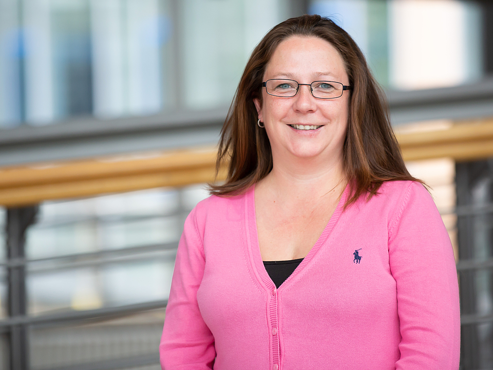 Mitarbeiterin lächelt in die Kamera.