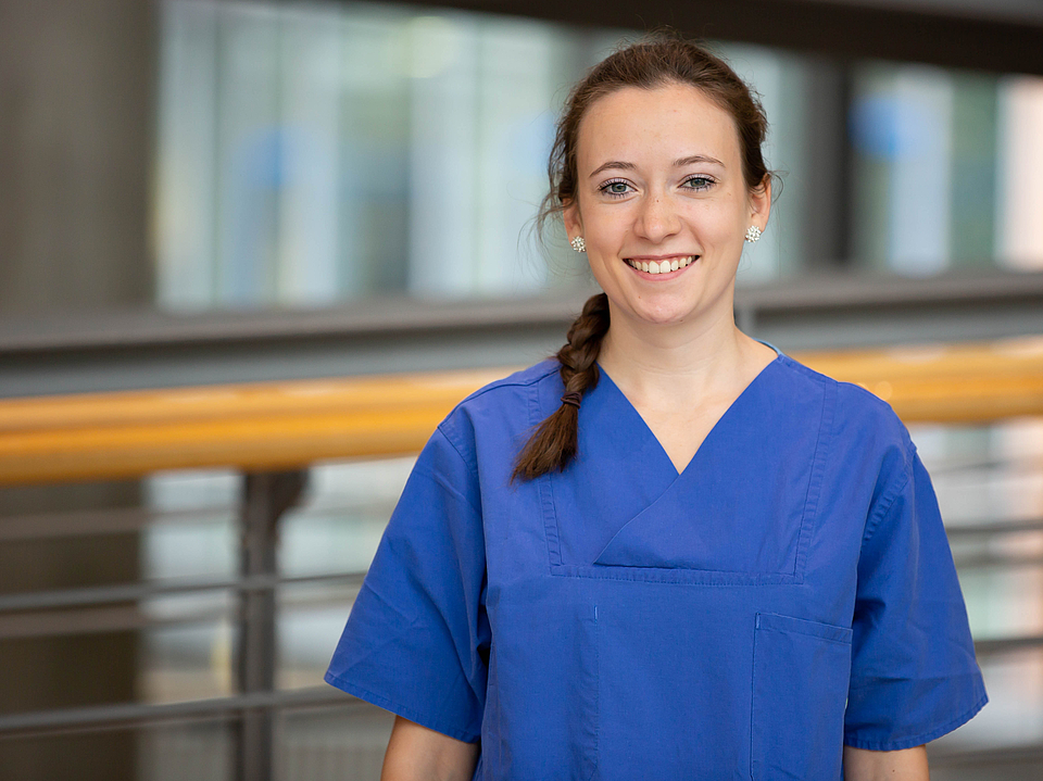 Pflegerin lächelt in die Kamera.