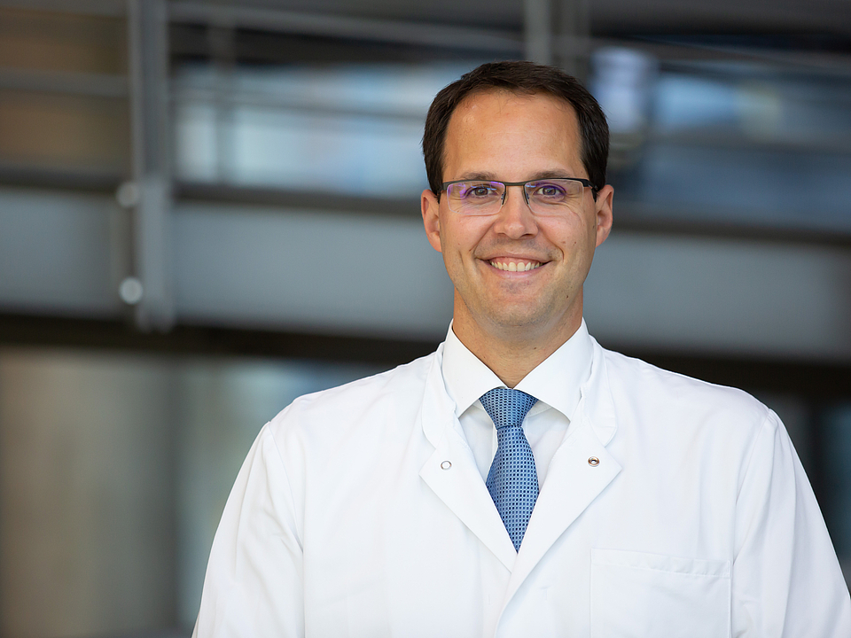 Ein Arzt lächelt in die Kamera.