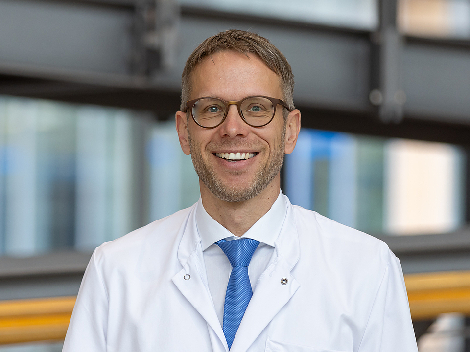 Arzt lächelt in die Kamera.