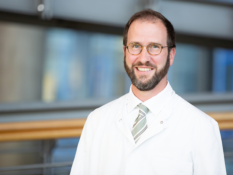 Ein Arzt lächelt in die Kamera.