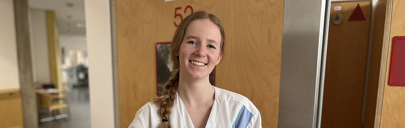 Eine Pflegerin hält ein Tablett mit dem Frühstück nach oben.