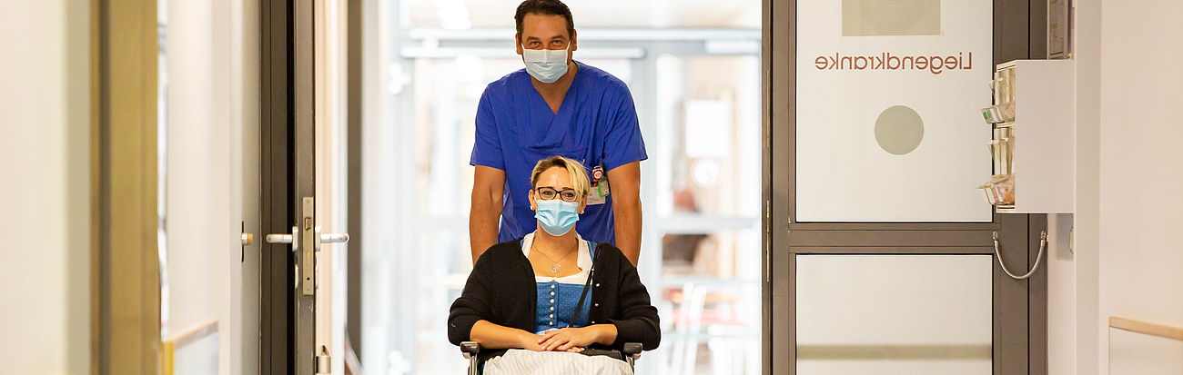 Patientin wird im Rollstuhl in die Notaufnahme geschoben