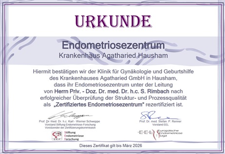 Rezertifizierungs-Urkunde Endometriosezentrum Krankenhaus Agatharied Eine Urkunde zur Rezertifizierung des Endometriosezentrums am Krankenhaus Agatharied in Hausham. Der Text bestätigt die erfolgreiche Überprüfung der Struktur- und Prozessqualität als "Zertifiziertes Endometriosezentrum" unter der Leitung von Herrn Priv.-Doz. Dr. med. Dr. h.c. S. Rimbach. Unten sind die Logos der Stiftung Endometriose Forschung und der Deutschen Gesellschaft für Gynäkologie und Geburtshilfe (DGGG) zu sehen. Das Zertifikat ist gültig bis Mai 2020.