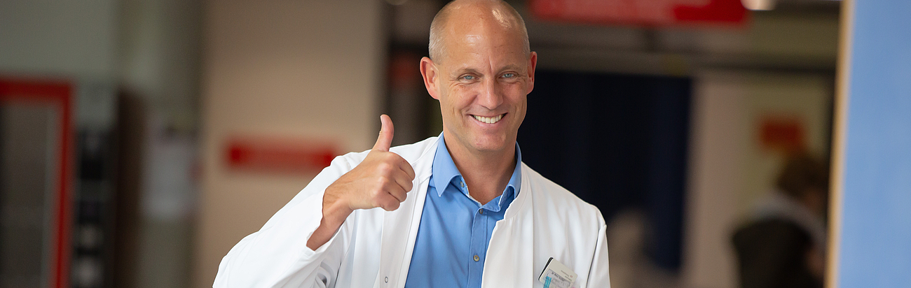 Dr. Wellner steht im Flur und macht einen Daumen nach oben.