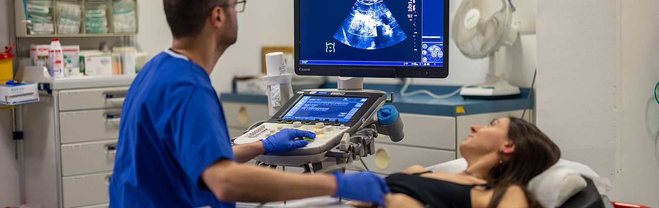Eine Patientin liegt auf einer Liege und ihr Bauchraum wird mithilfe von Ultraschall untersucht.