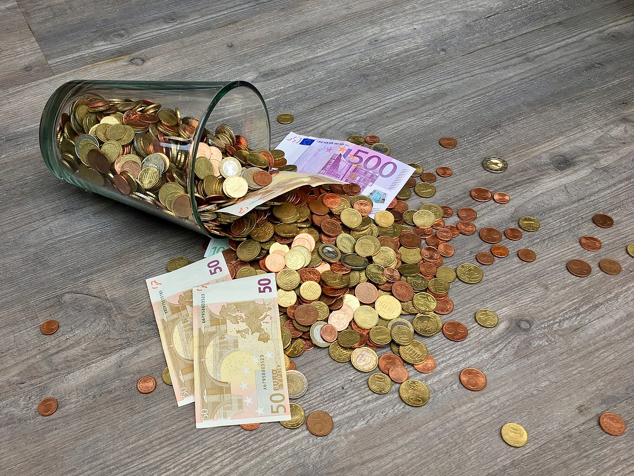 Spardose Eine umgeworfene Spardose aus der Geld fällt.