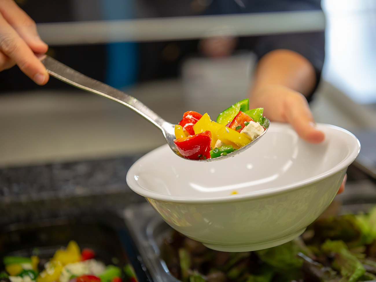Hochwertige Lebensmittel in der Kantine Mitarbeiterin nimmt sich Salat vom Salatbuffet
