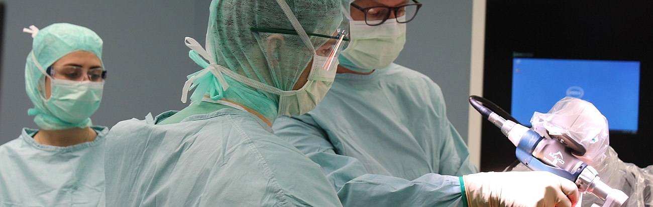 Ärzte bei Operation mit Roboterarm