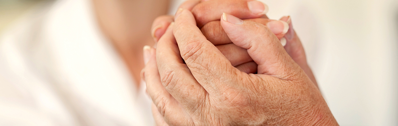 Ärztin hält Hand eines alten Menschen